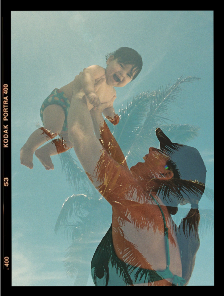A double exposure photograph showing Maria lifting up her son, with palm trees and a blue sky superimposed.