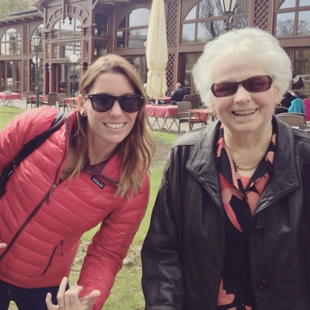 Maria and her grandmother wearing sunglasses outside at a restaurant with outdoor seating in Germany.