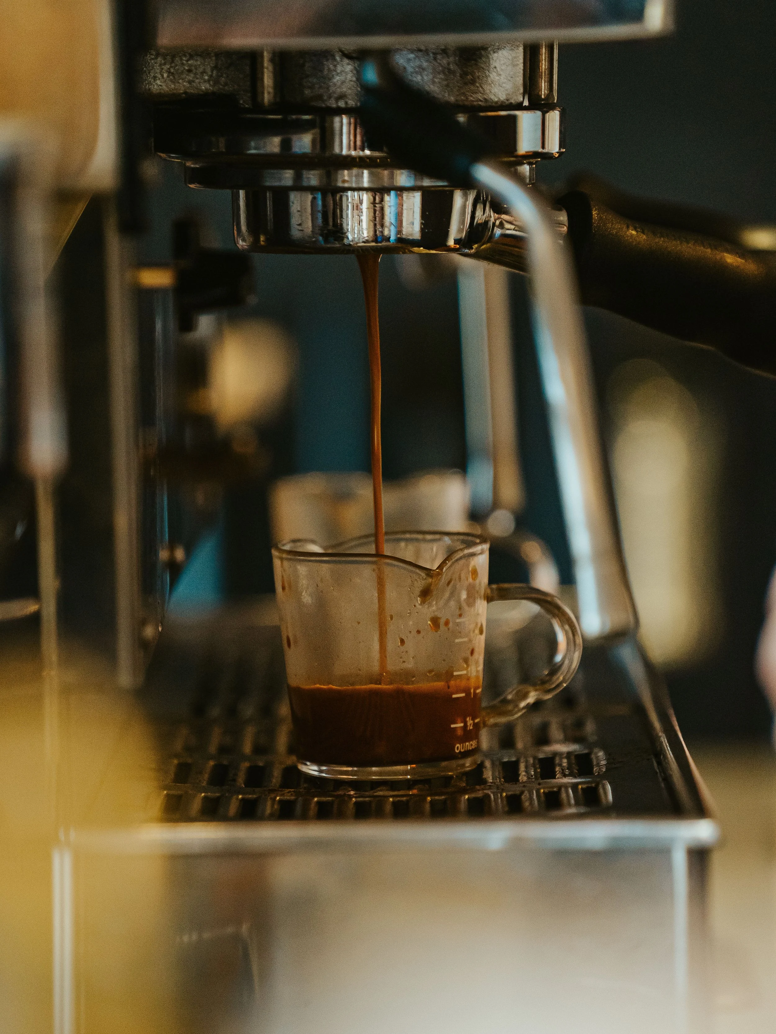 Close-up of a coffee machine pouring espresso into a glass mug.