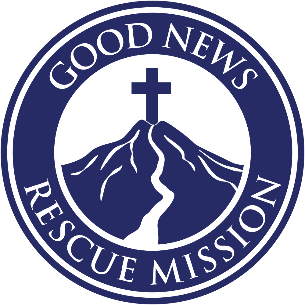 A circular logo with a dark blue border and white background, featuring the words 'Good News Rescue Mission' around the circumference. In the center, there is a mountain with a cross on top and a path leading to it.