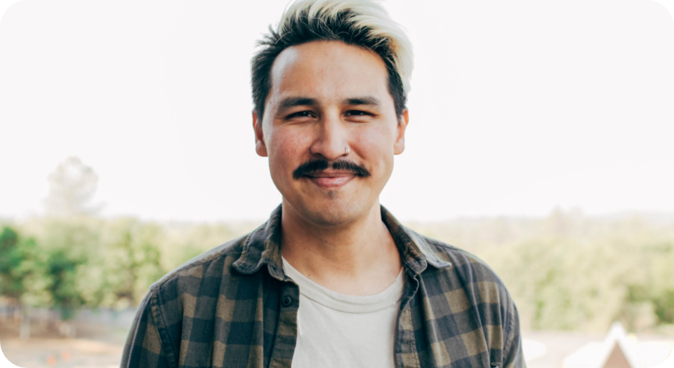 Smiling man with a mustache and dyed blonde hair outdoors