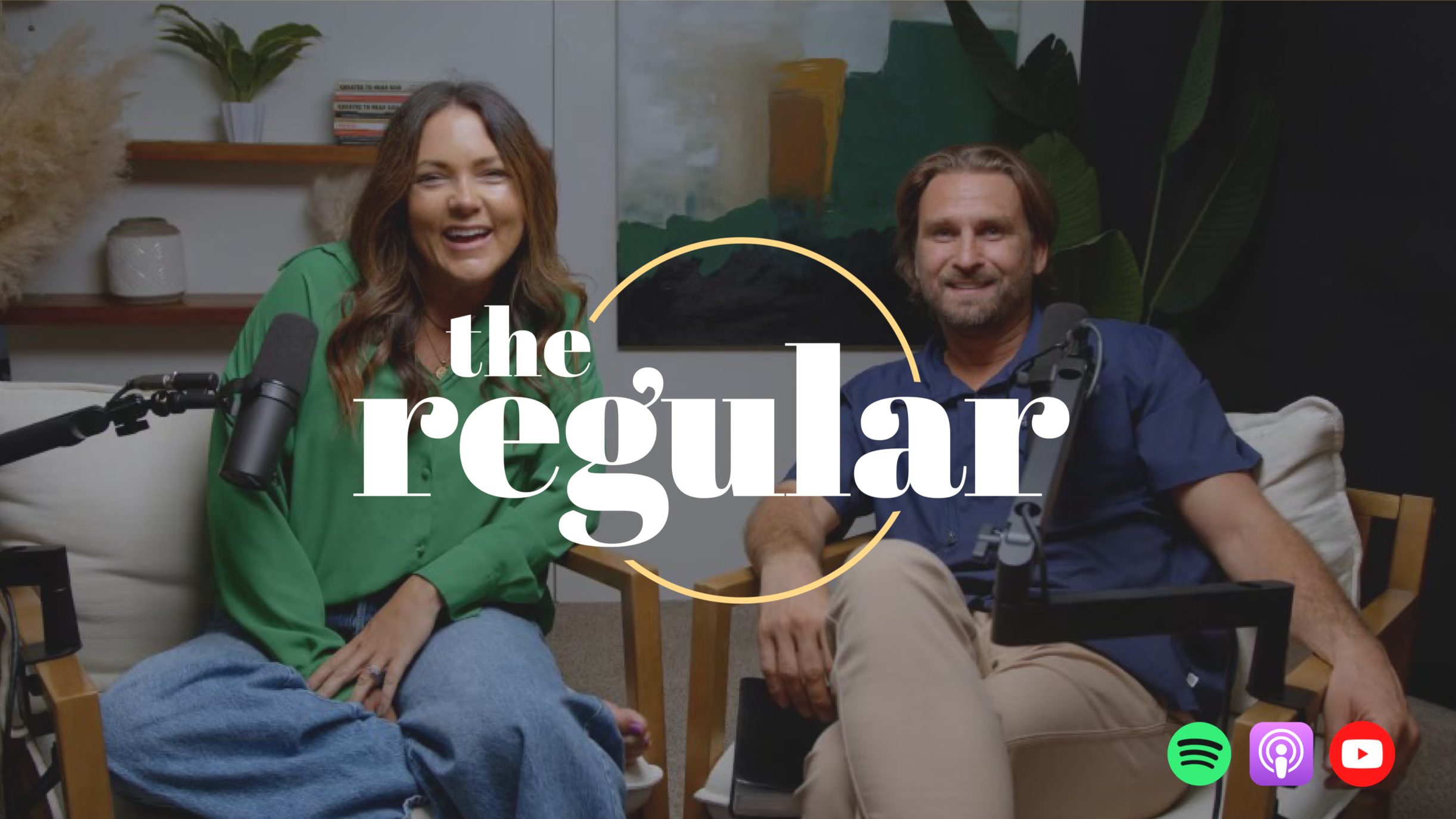 Two people sitting in a casual setting with microphones, a laptop, and podcast setup. Woman in green top smiling, man with beard in blue shirt. Text overlay says "the regular" with colored circle design.