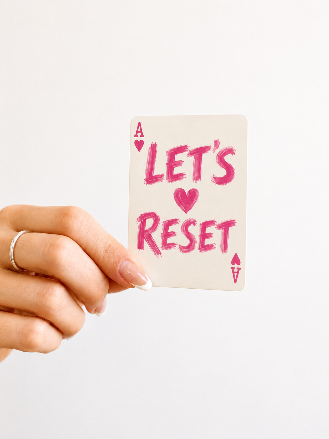 Hand holding the Let's Reset playing card motivational sticker — Lauren Stewart Project Love My Life Again shop