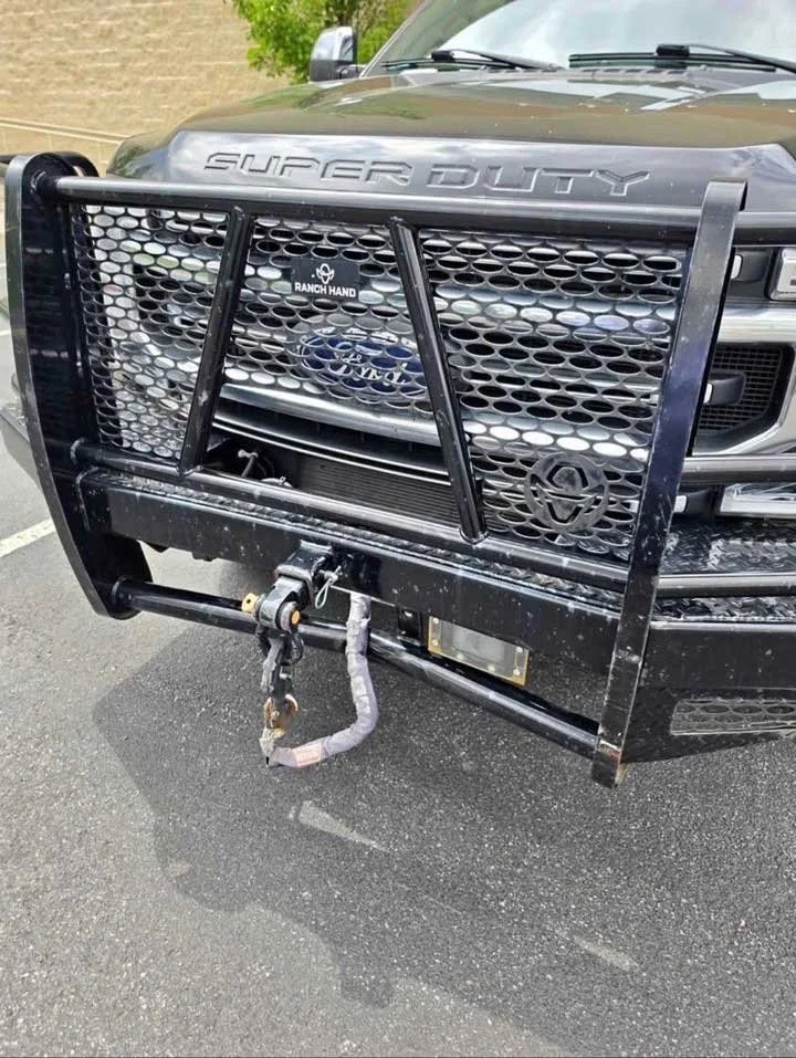 Close-up of the front of a Ford Super Duty truck with a black metal grille guard and tow hitch.