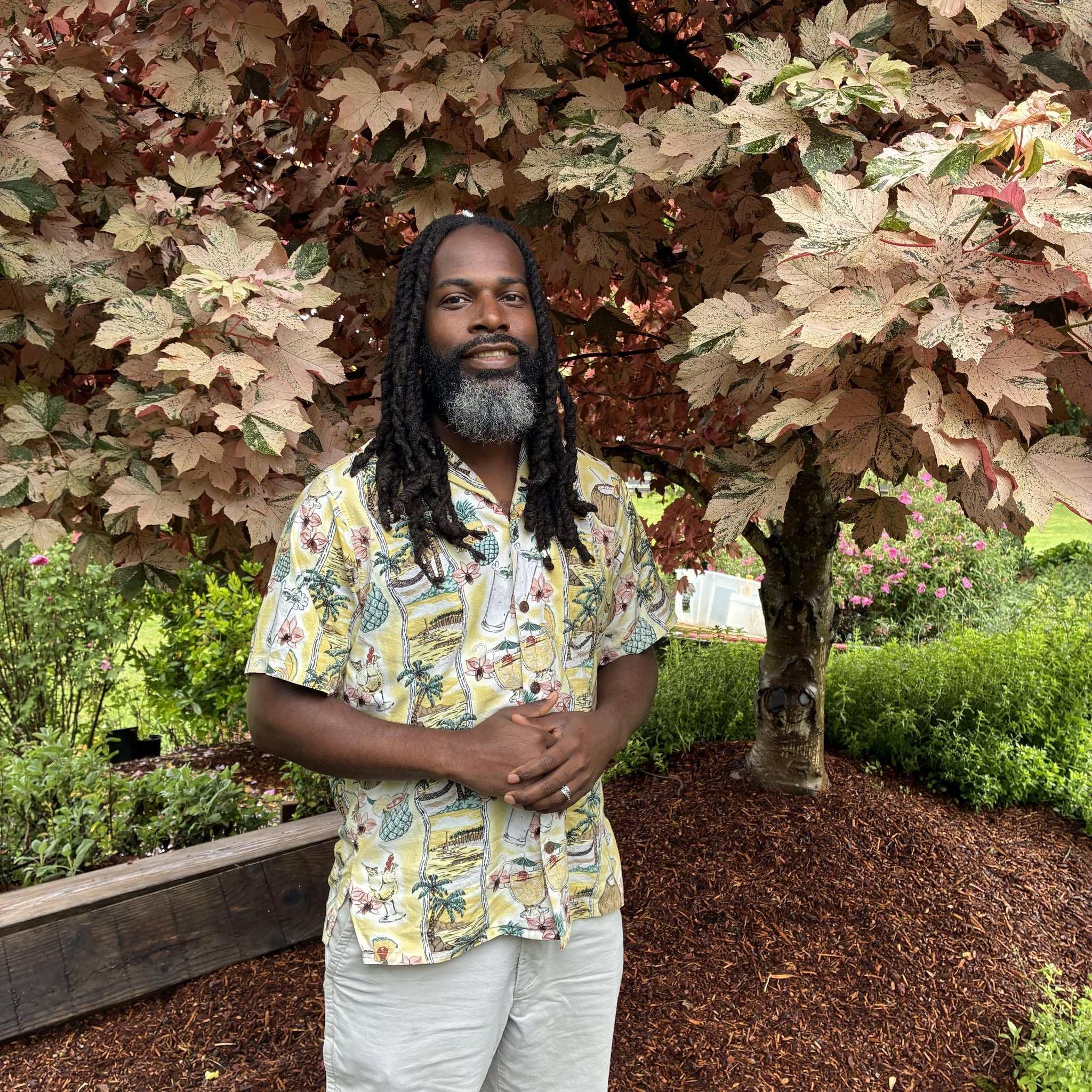 man with locs standing in front of white speckled maple tree
