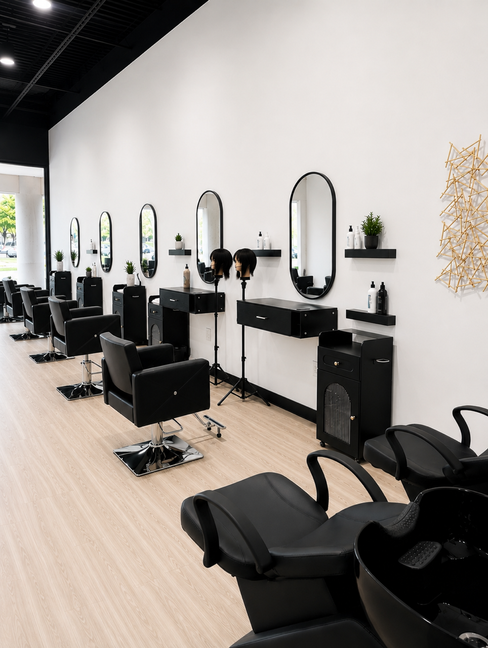 Empty modern hair salon with black chairs, mirrors, and shelves holding hair products, with a light wood floor and white walls.