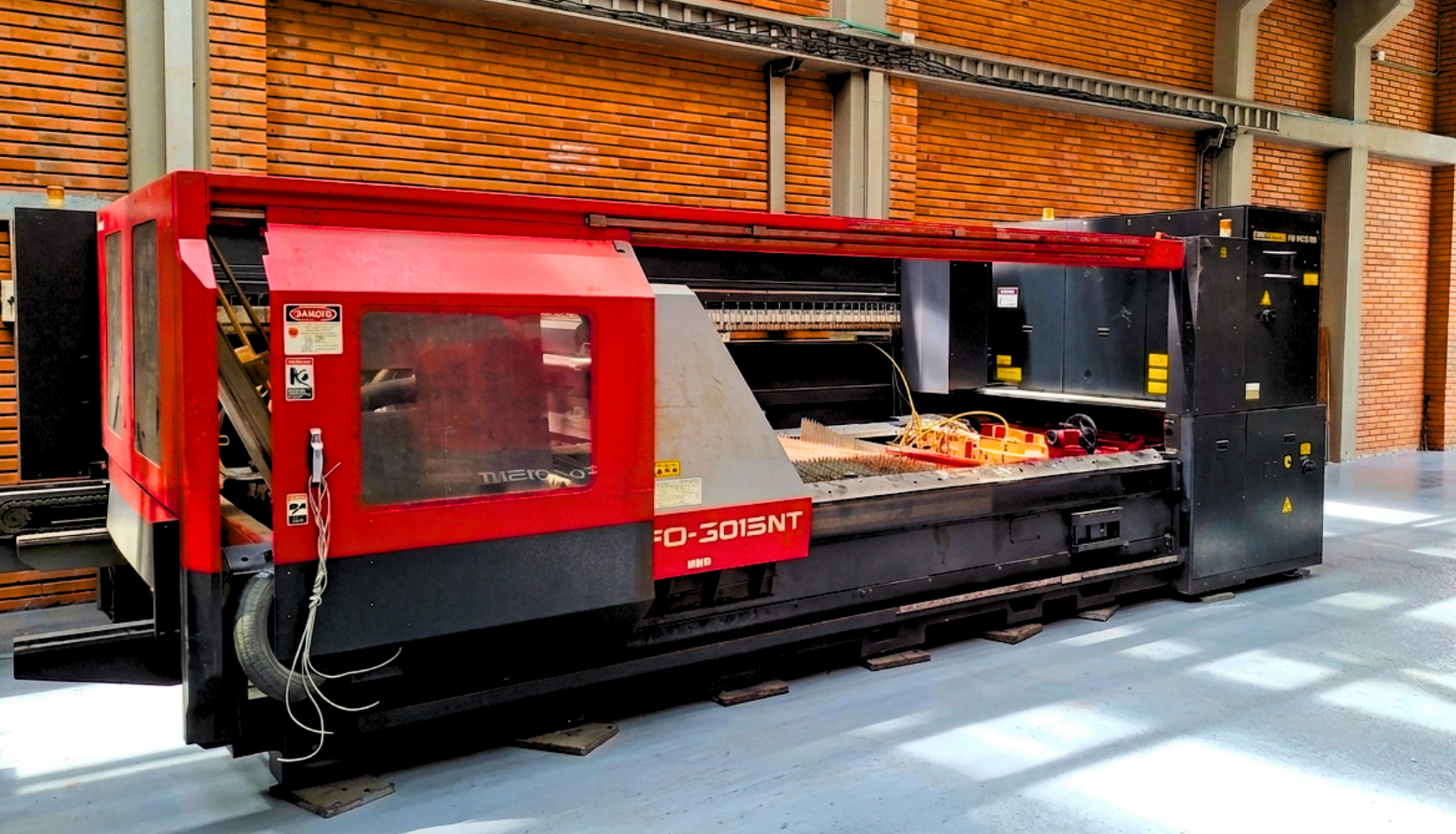 Maquina CNC de gran tamaño en un taller industrial con paredes de ladrillo.