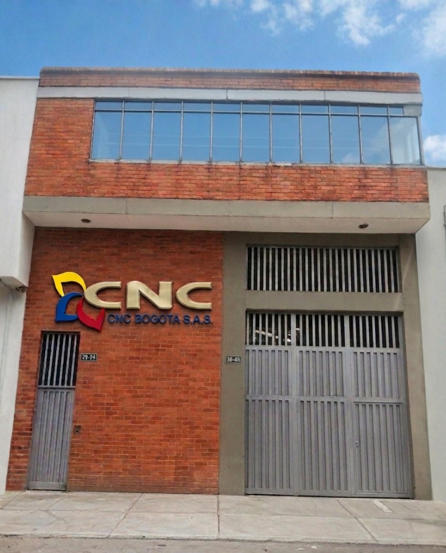 Edificio de ladrillo con un letrero que dice CNC Bogotá S.A.S. y una puerta metálica grande.