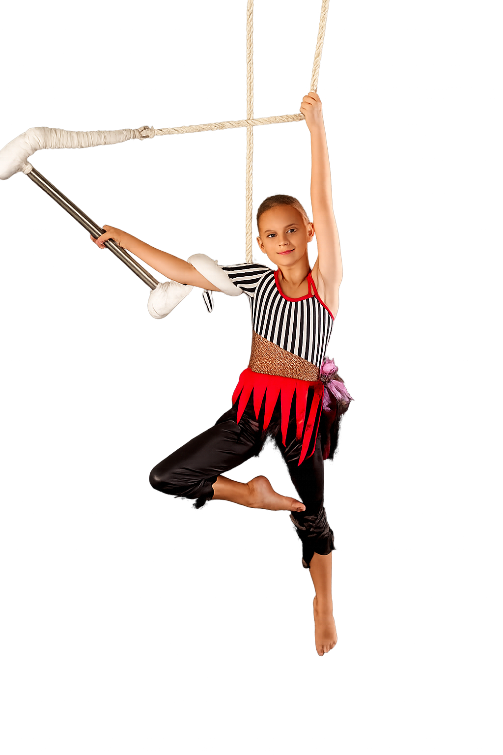 Young girl dressed in a circus performer costume hanging from a trapeze.