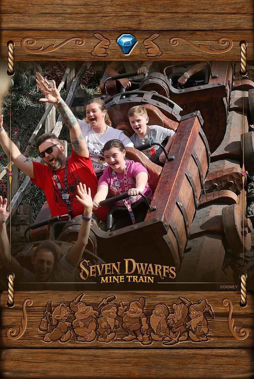 People riding the Seven Dwarfs Mine Train roller coaster at Disney, smiling and waving.