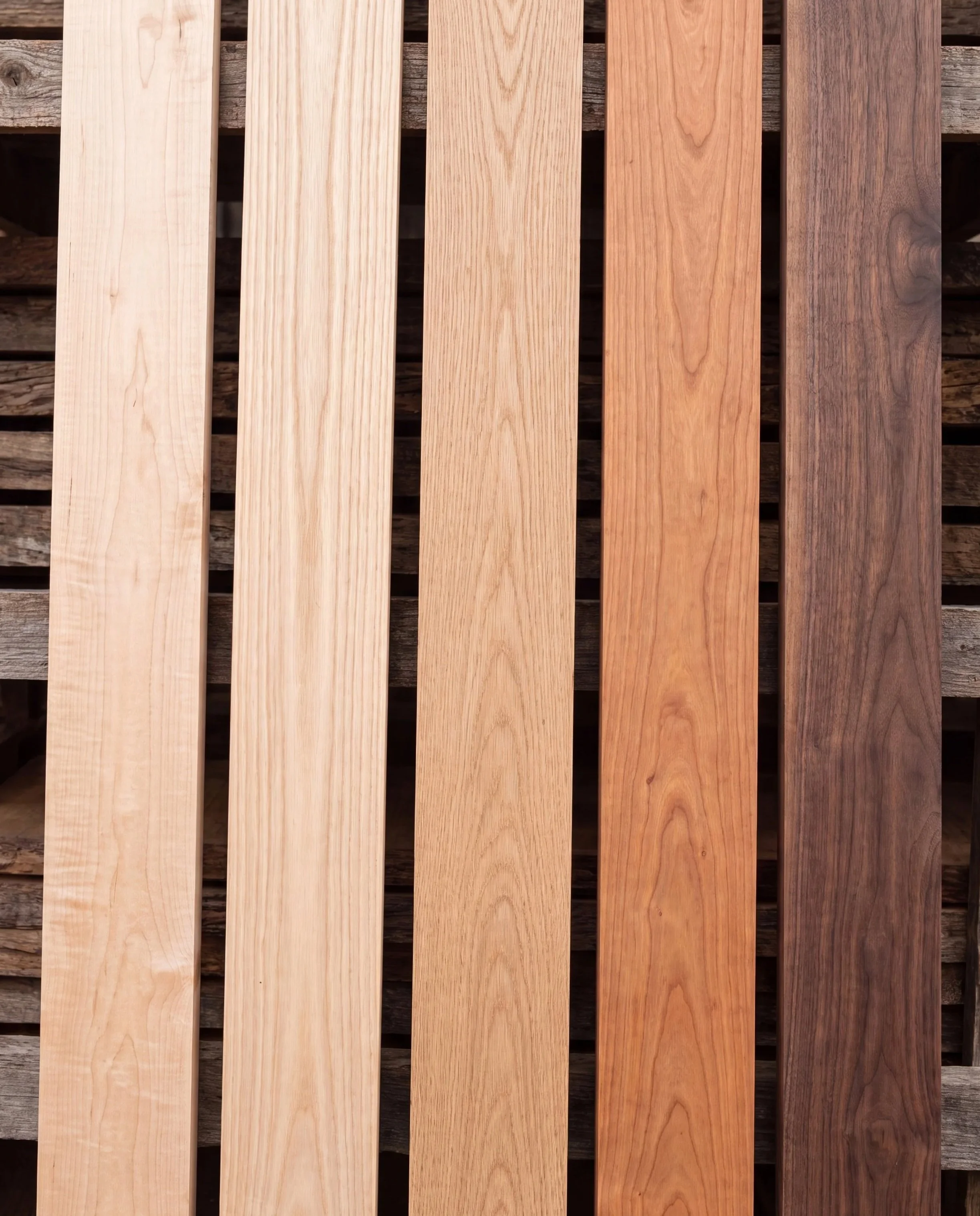 Close-up of wooden slats in varying shades from light to dark, arranged parallel on a wooden surface.