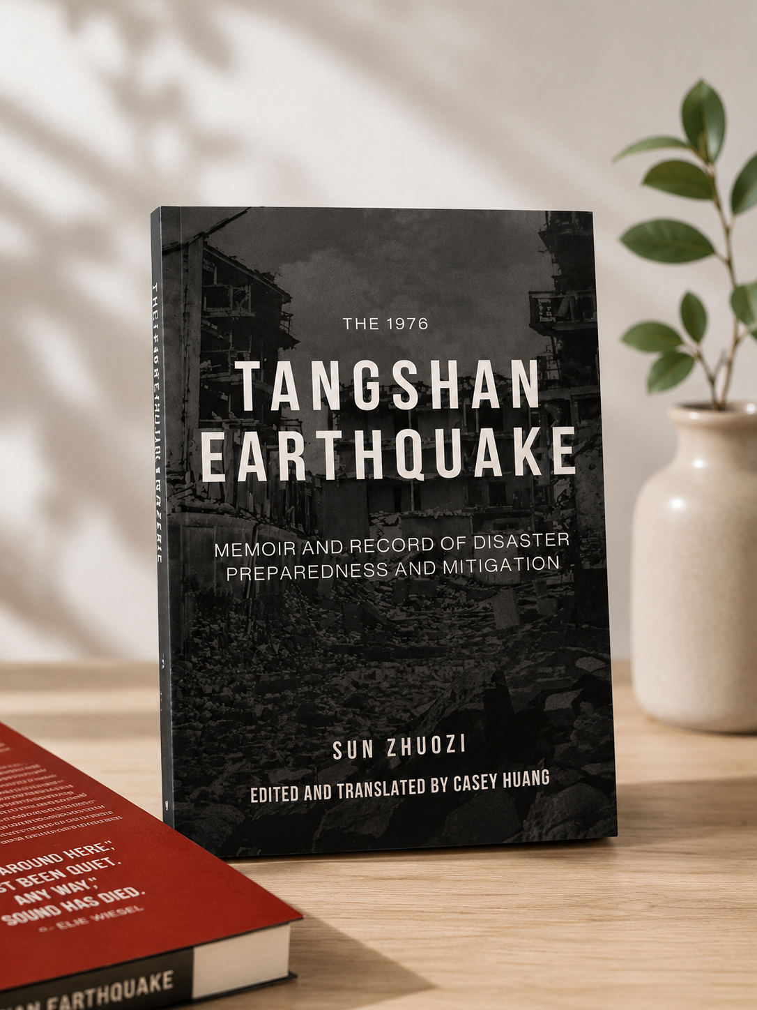 Printed edition of The 1976 Tangshan Earthquake: Memoir and Record of Disaster Preparedness and Mitigation displayed on a wooden table beside a potted plant.