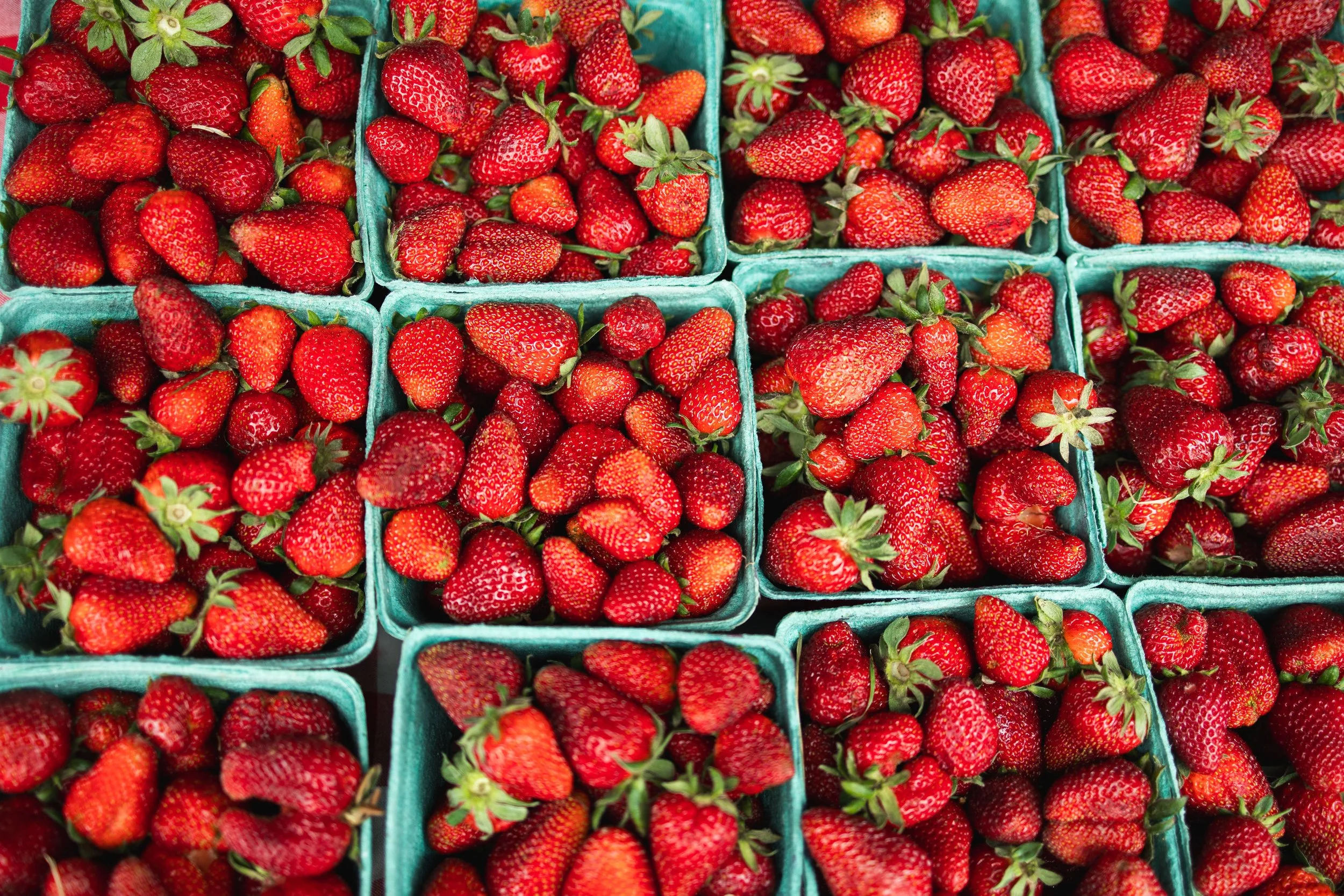 Multiple baskets filled with fresh strawberries at a market.