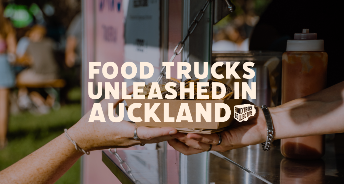 Close-up of a food vendor handing a paper tray to a customer at a food truck event in Auckland, with blurred people and food trucks in the background.