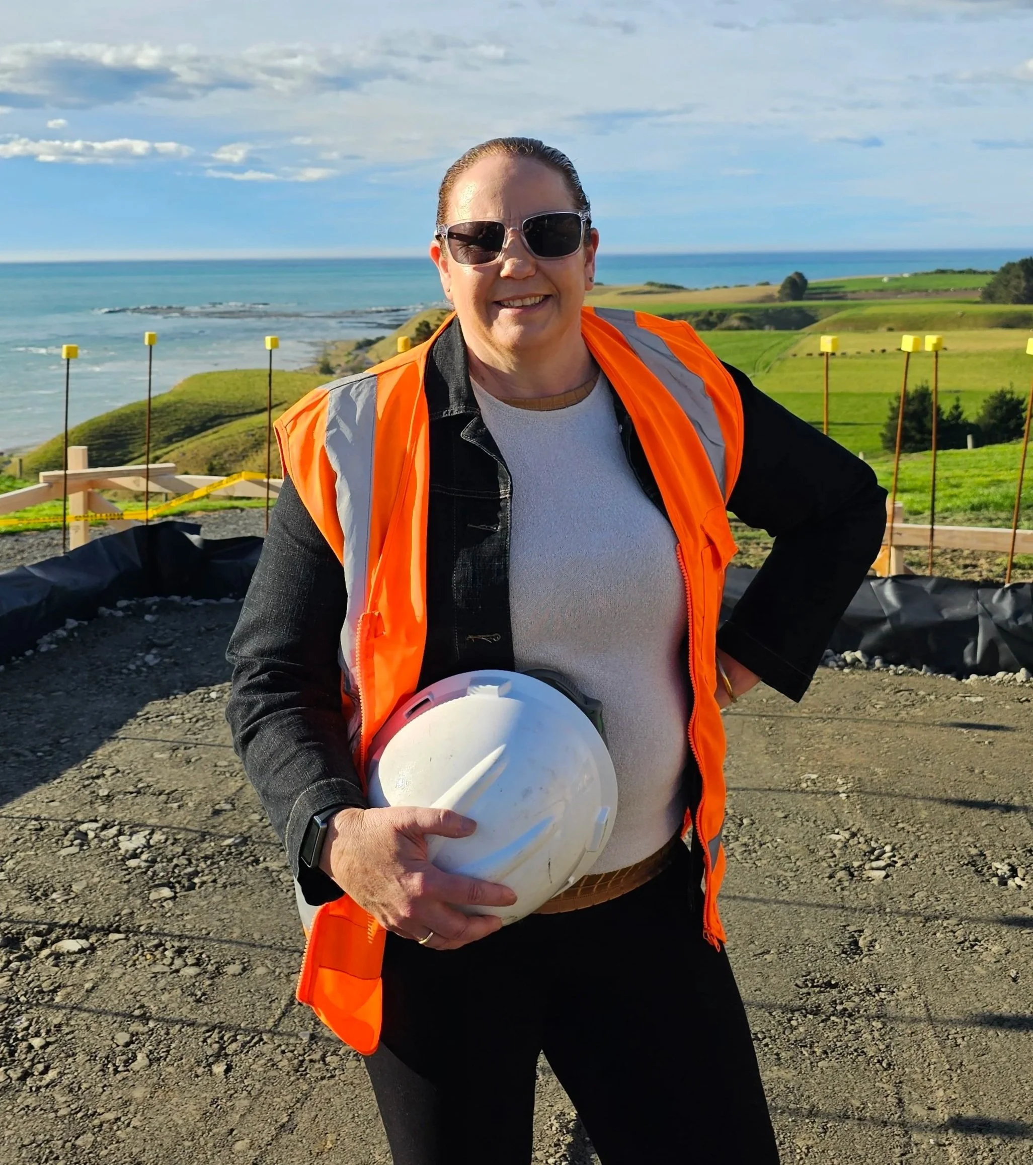 Bonita wearing high-visibility safety gear and holding a hard hat during a visit to a New Zealand worksite.