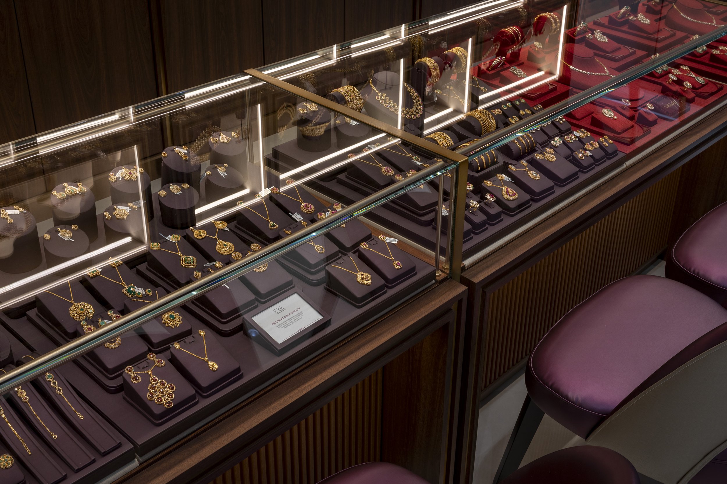 Jewelry display case filled with gold and gemstone necklaces, earrings, and bracelets in a jewelry store.