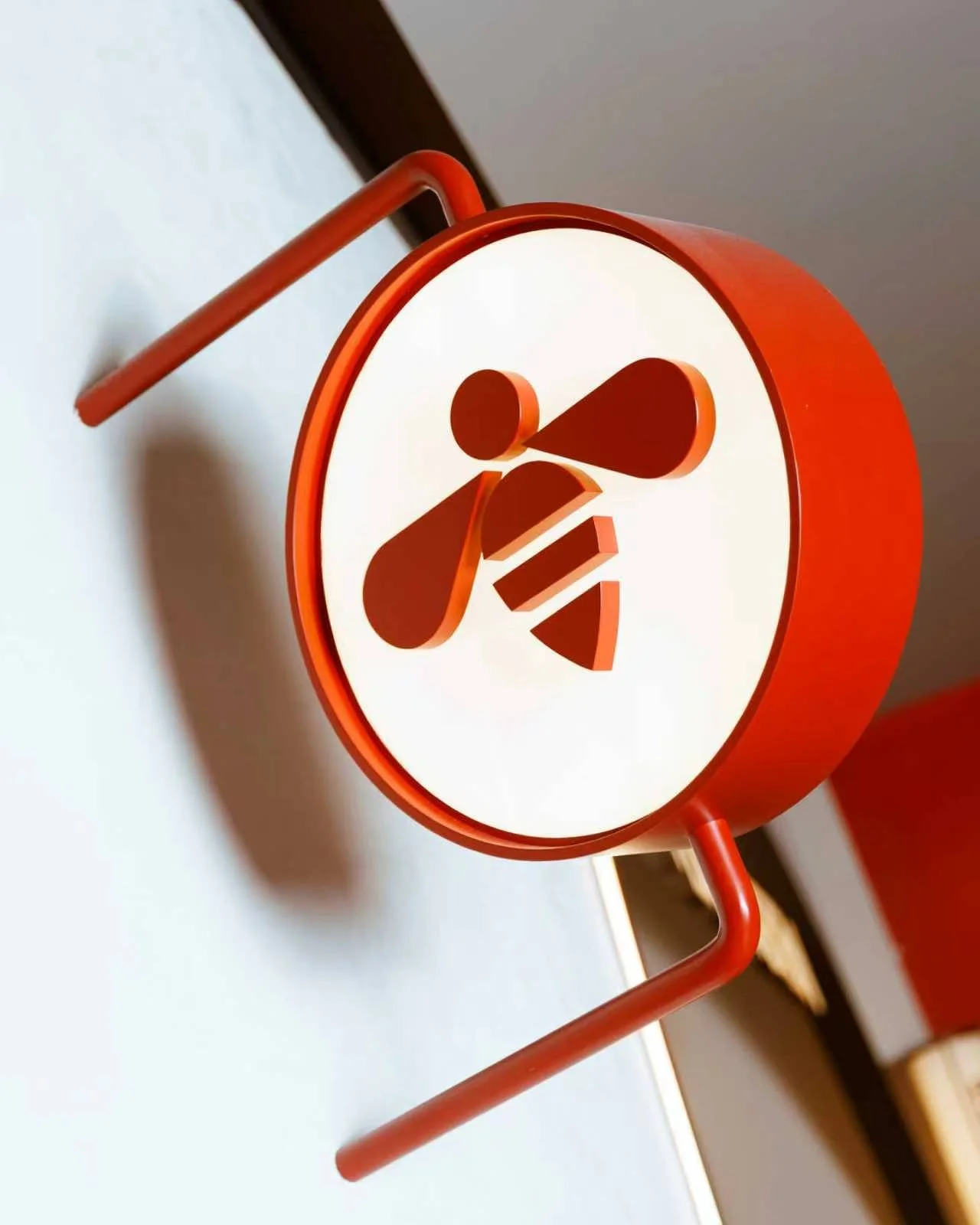 Bee Keen logo on a white sign affixed to a white wall.