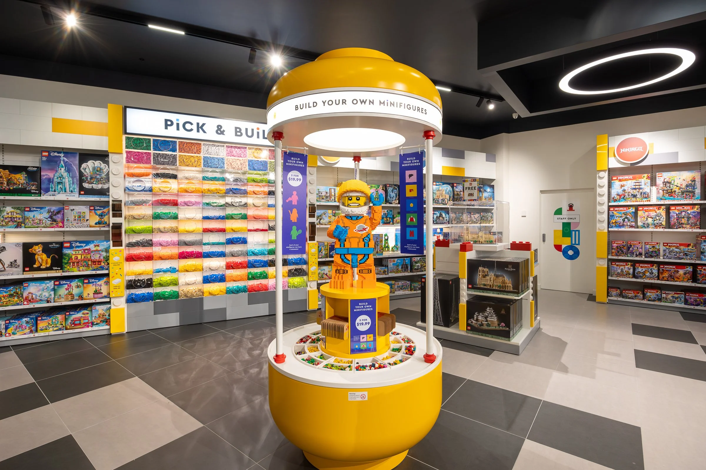 A LEGO store with shelves of LEGO sets, a colorful bead display, and a LEGO minifigure display.