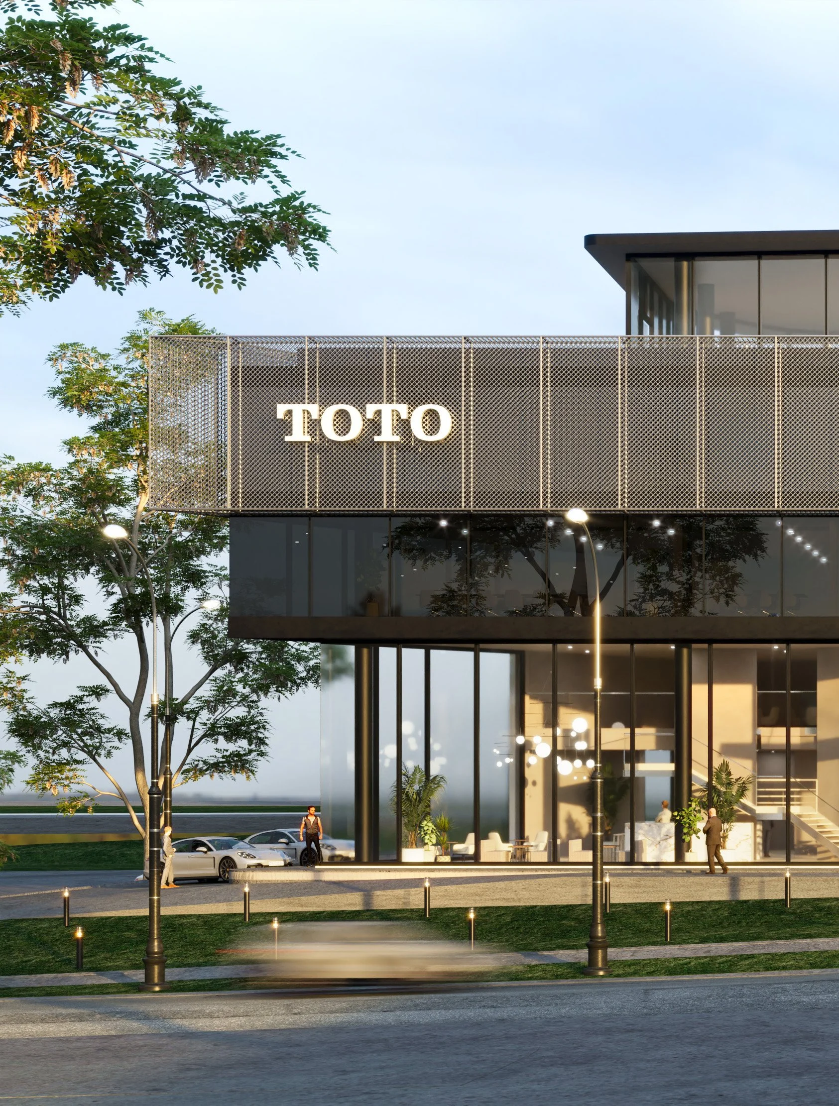 Modern building with a sign that says 'TOTO', large glass windows, trees, and people walking outside in the evening.