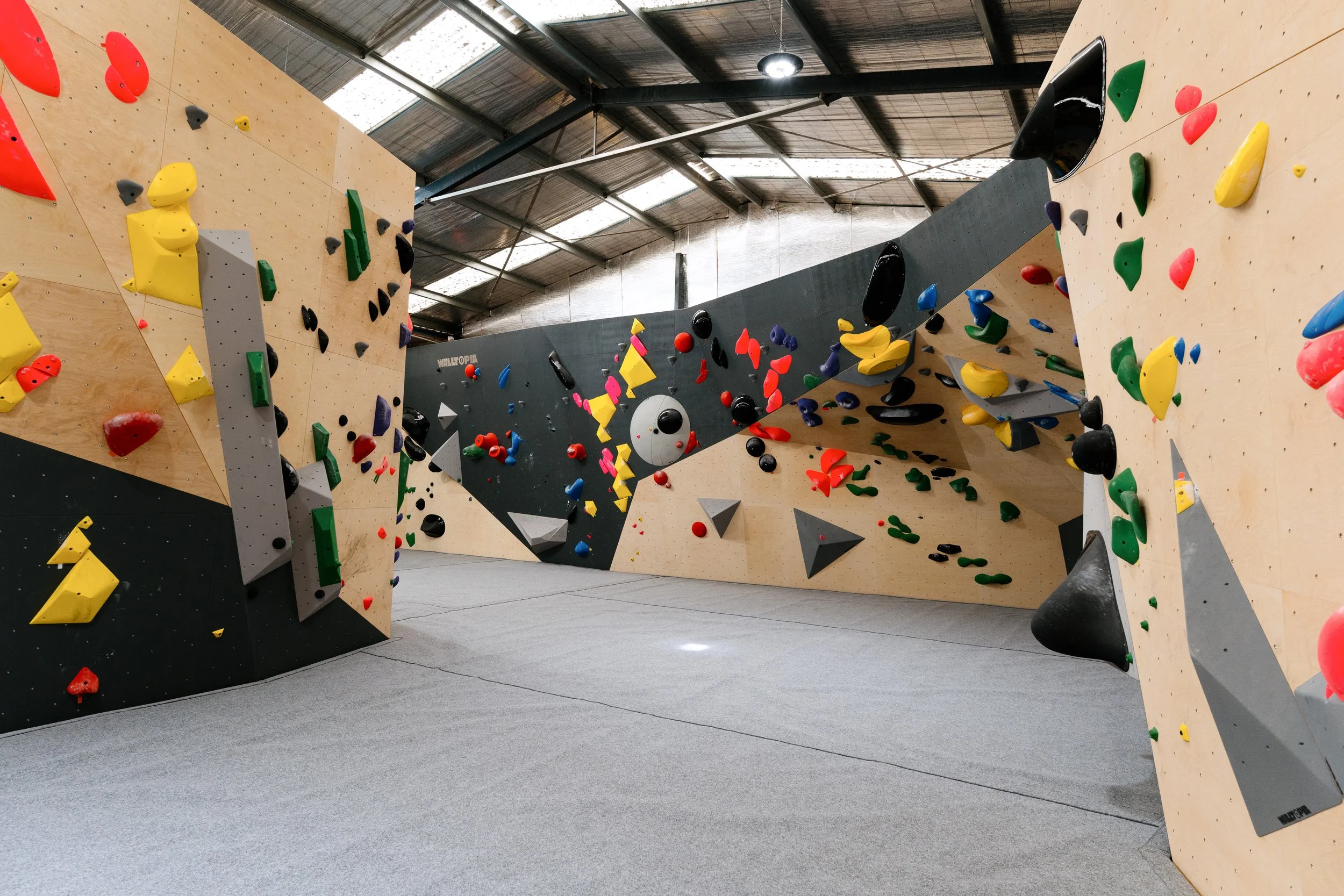 Indoor bouldering gym with various colored climbing holds and walls.