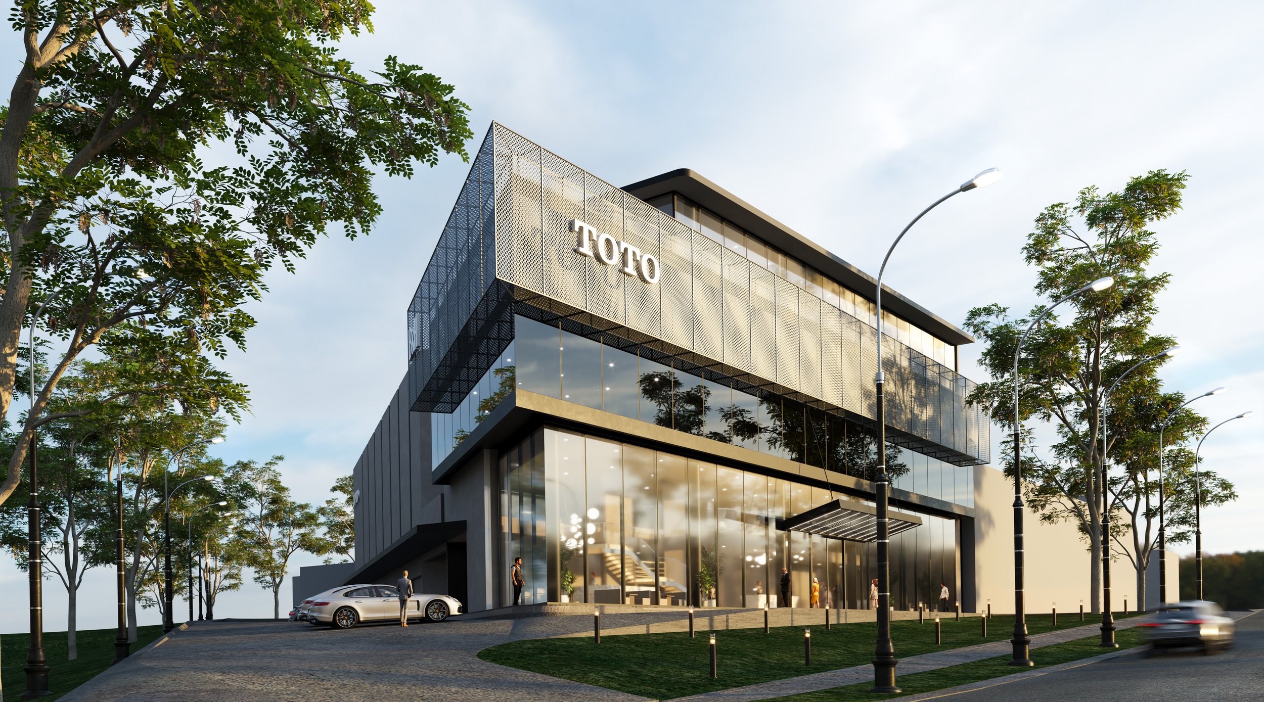 Modern multi-story building with the name 'TOTO' on the upper facade, surrounded by trees, street lamps, and parked cars, under a partly cloudy sky.