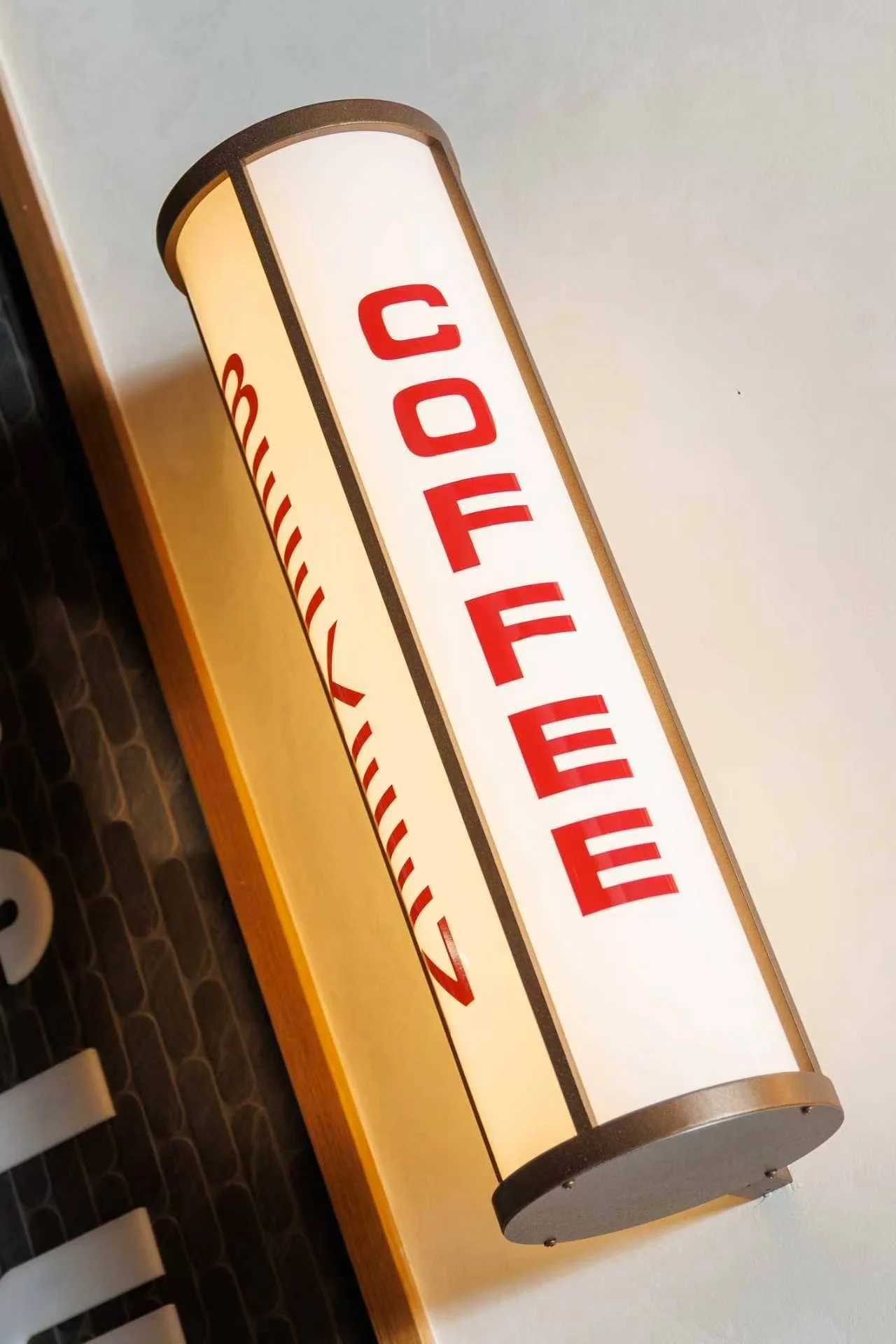 A vintage-style sign with the word 'COFFEE' in red letters on a cream-colored background, mounted on a wooden surface.
