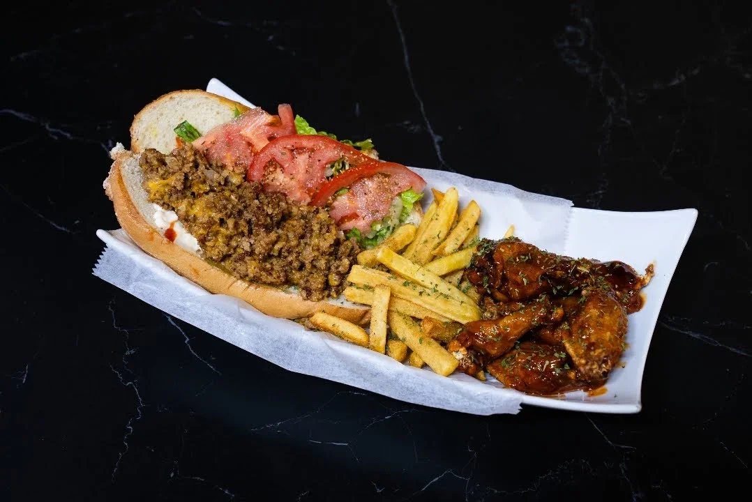 Hot dog with ground beef, lettuce, tomato, yellow fries, and chicken drumsticks with sauce