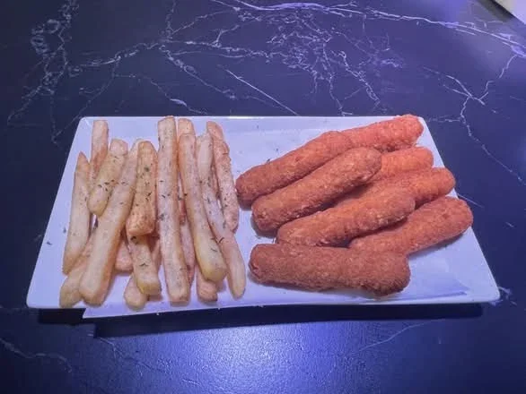 A white rectangular plate with French fries on the left and mozzarella sticks on the right, placed on a dark marble countertop.