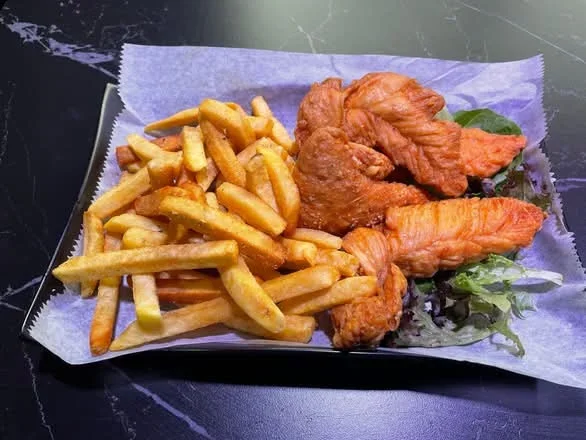 Fried fish fillets with French fries served on a white paper-lined tray