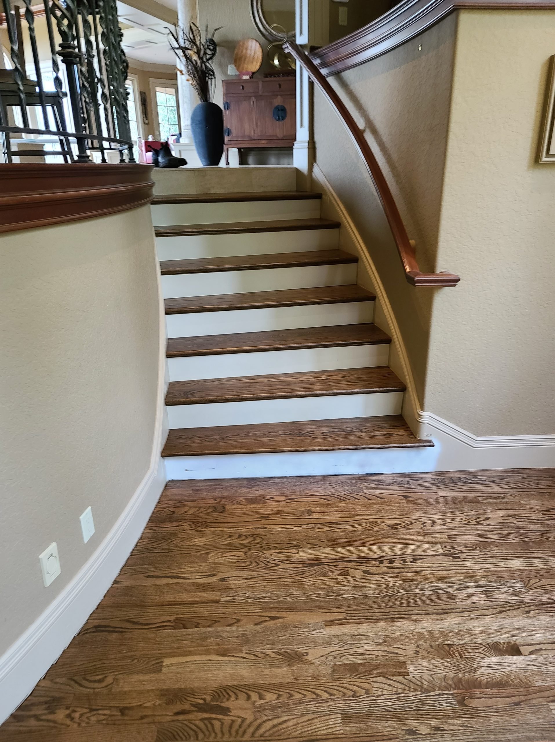 Photo of a staircase with wooden steps, beige walls, and white trim, leading to an upper level in a home interior.