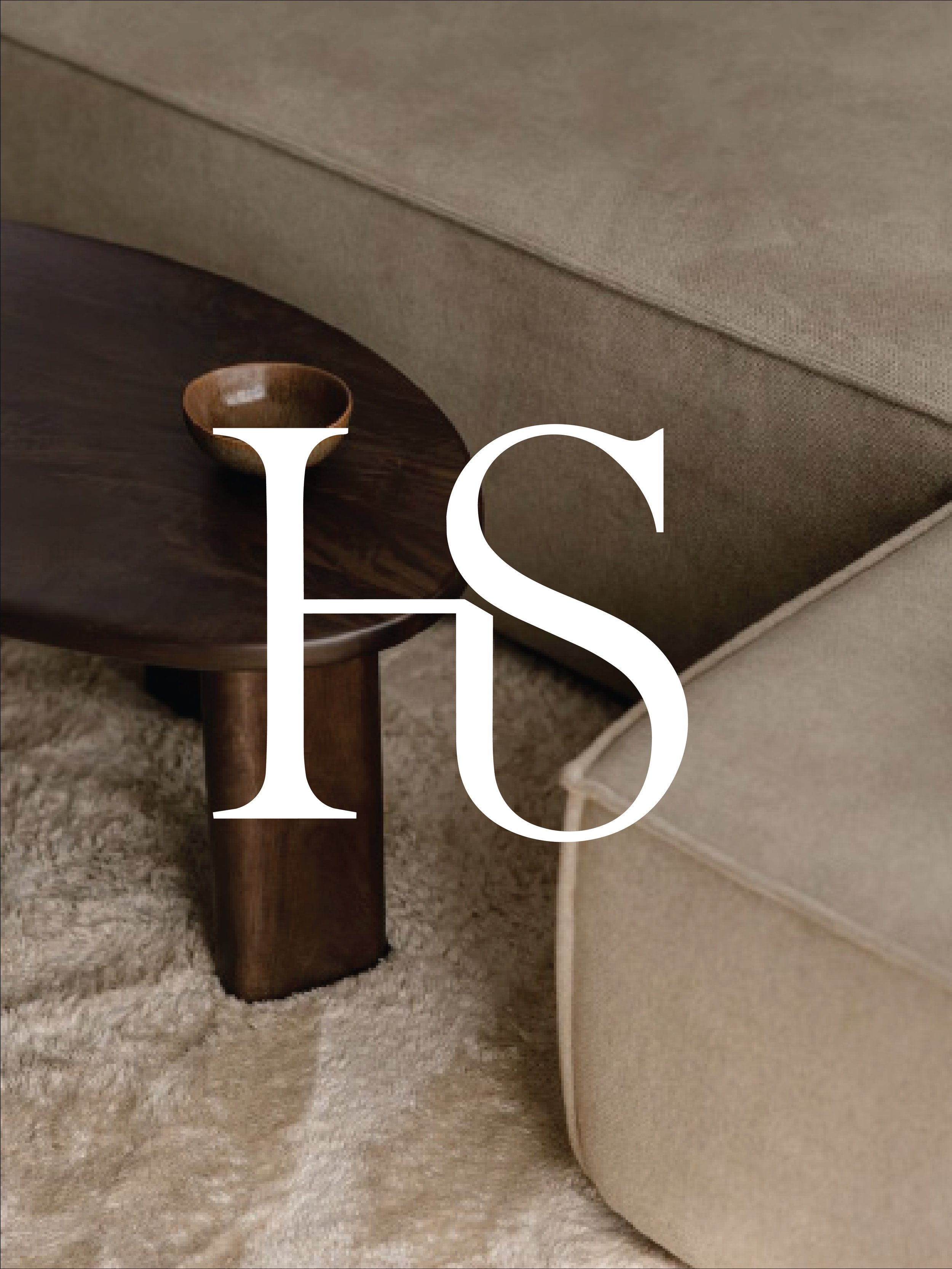 Close-up of a dark wooden table with a small wooden bowl resting on it, next to a beige sofa and a light-colored carpet.