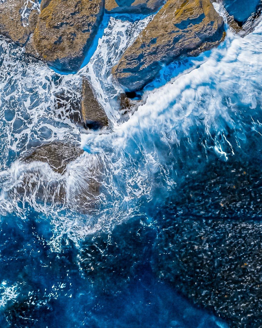 Ocean waves crashing against rocks, creating white foam and spray.