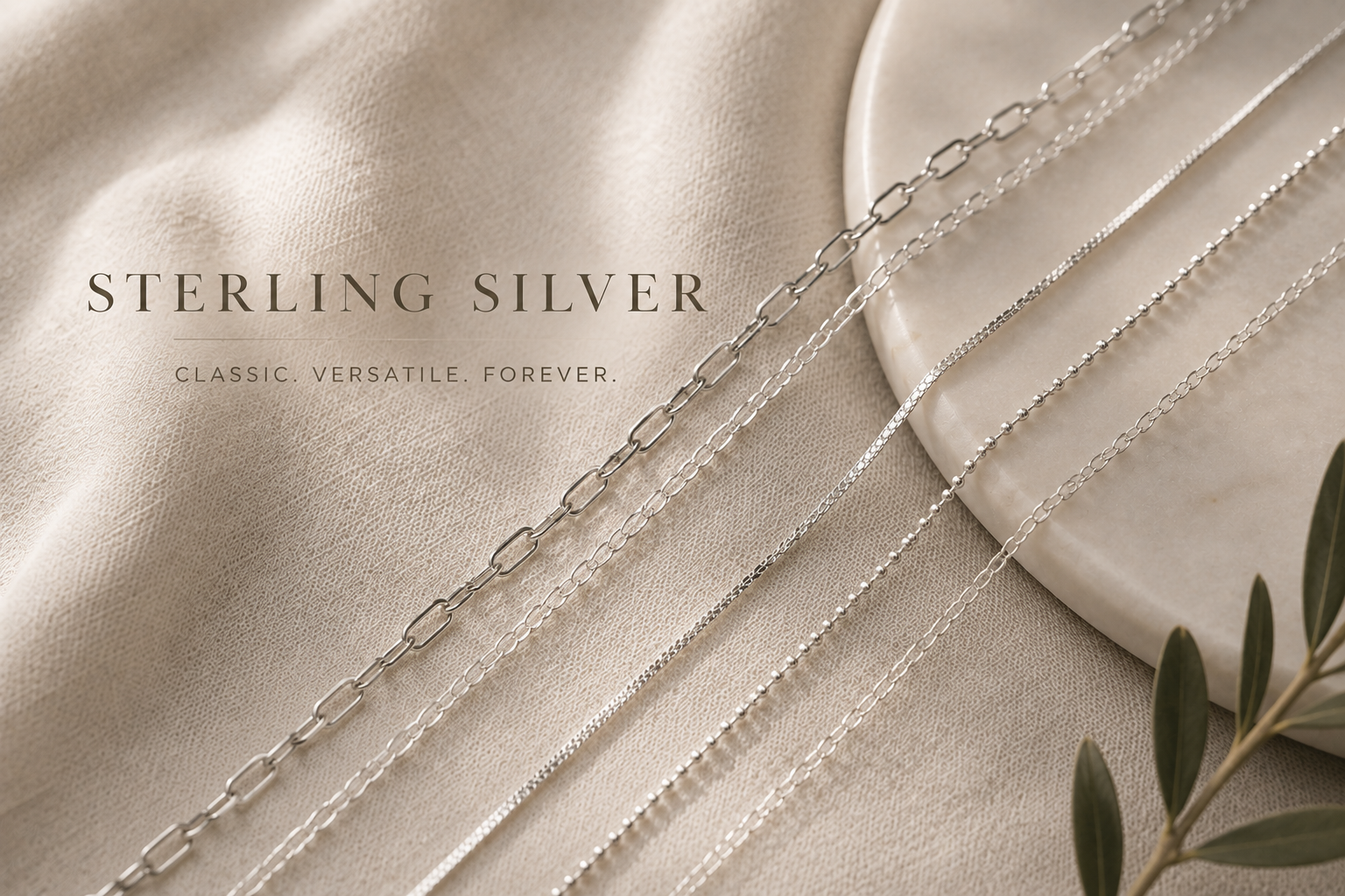 Various silver jewelry necklaces displayed on a beige fabric background with text 'Sterling Silver, Classic. Versatile. Forever.'