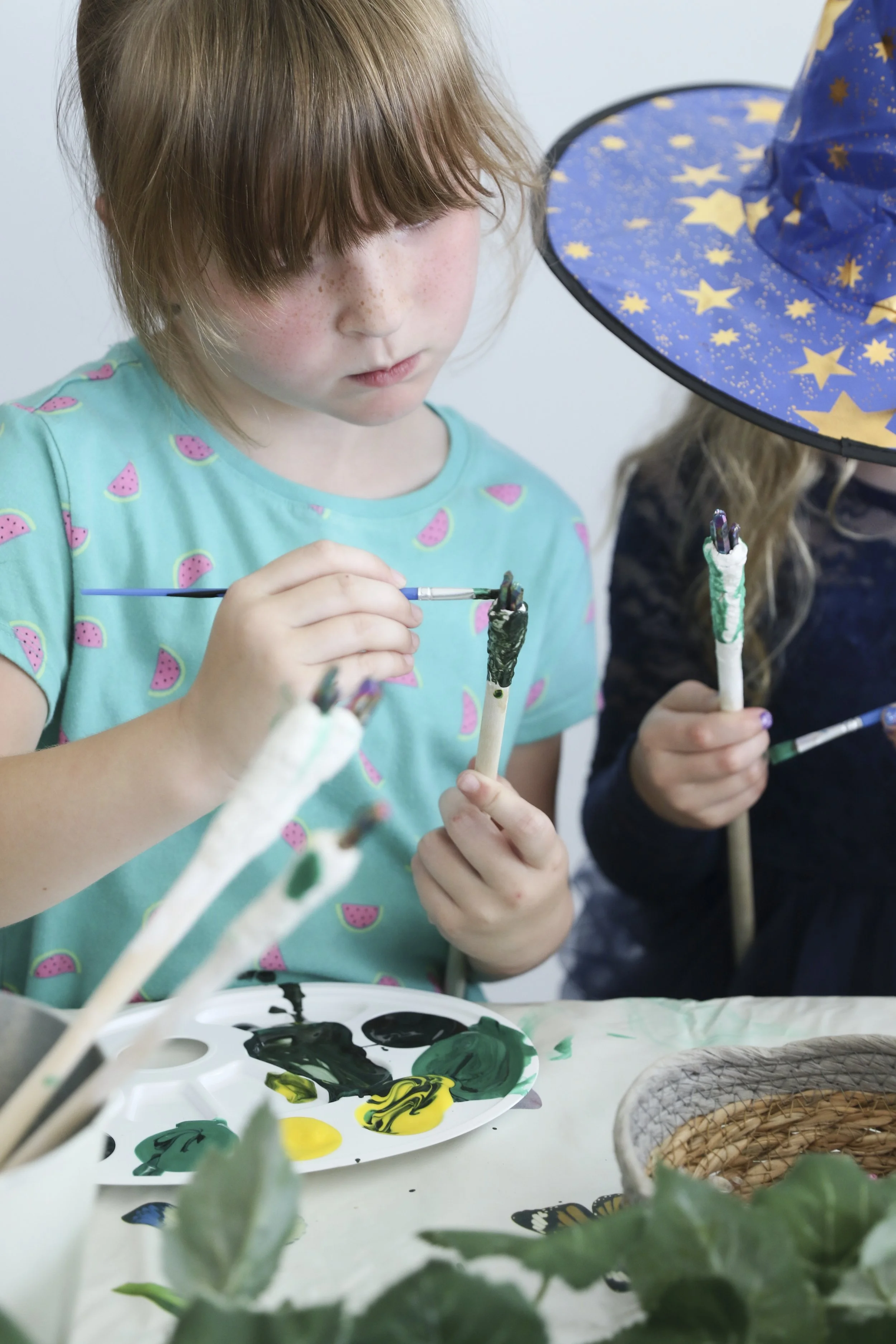 A young child focused on painting a magical craft object with a brush.