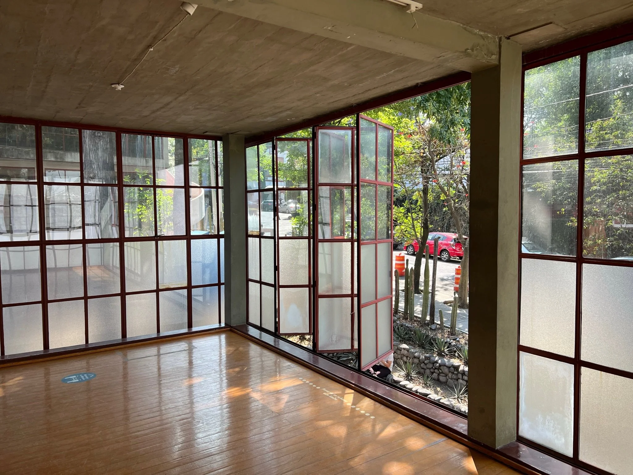 Architectural interior with concrete ceiling, wood floors, and red-framed windows