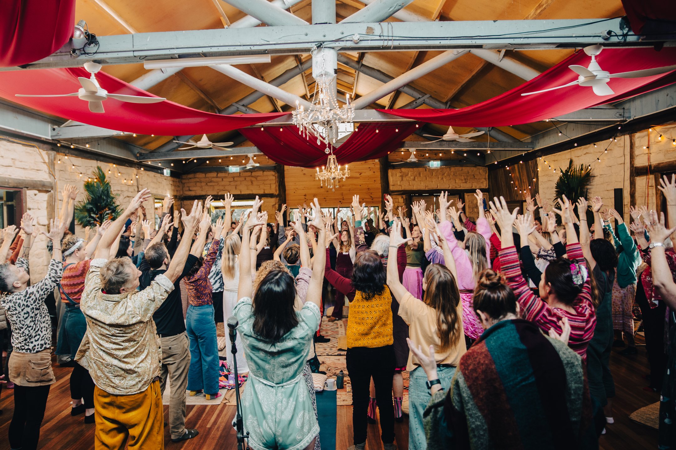 Participants raising their hands together during a Big Time Choir community singing experience led by Angie Rei.