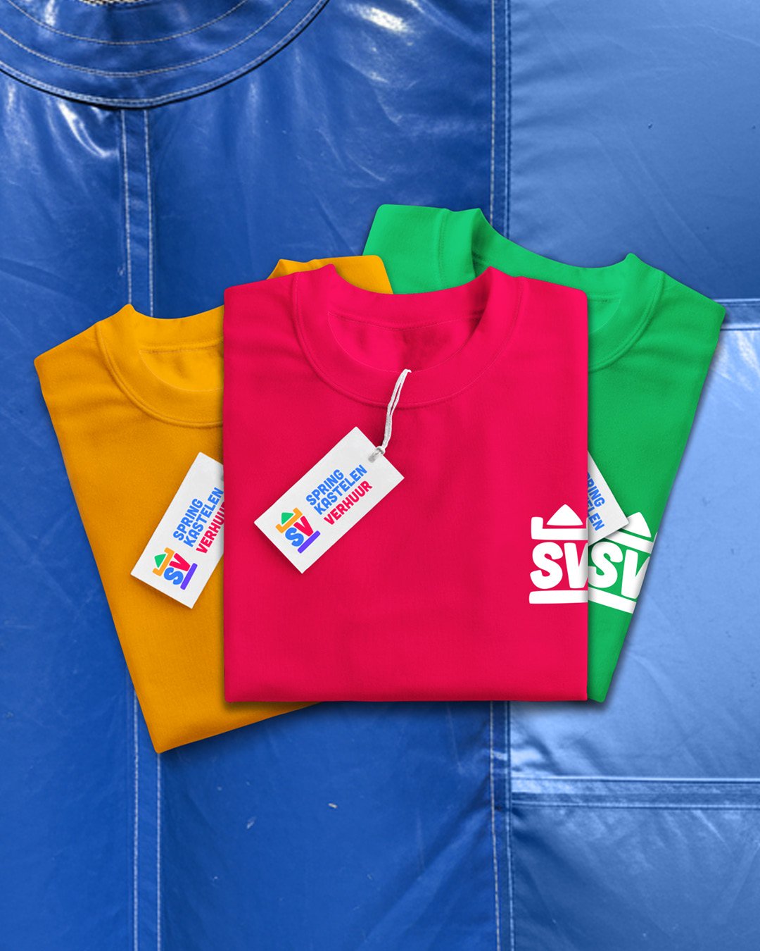 Three folded T-shirts in yellow, pink, and green with tags on top, placed on a blue bounce house surface with a blue background.
