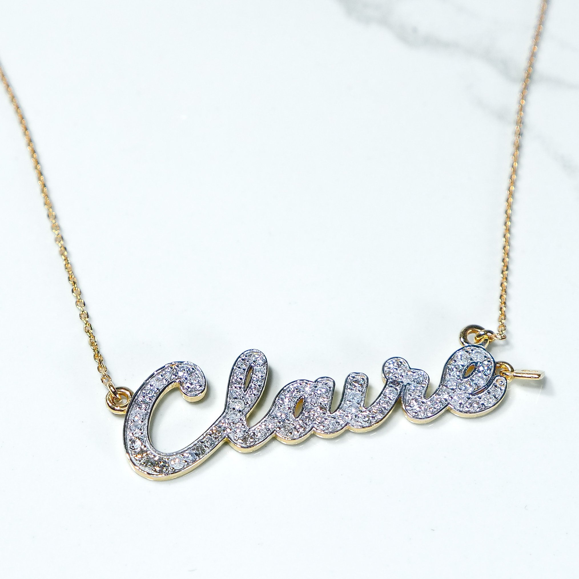 Close-up of a custom script name pendant with lab-grown diamonds, 9k gold