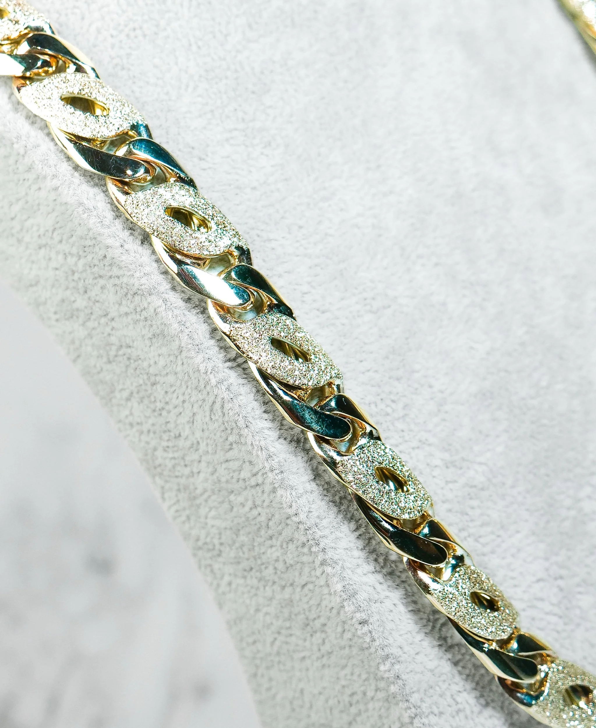Close-up of alternating high-polish and sandblasted birdseye links in 9k gold