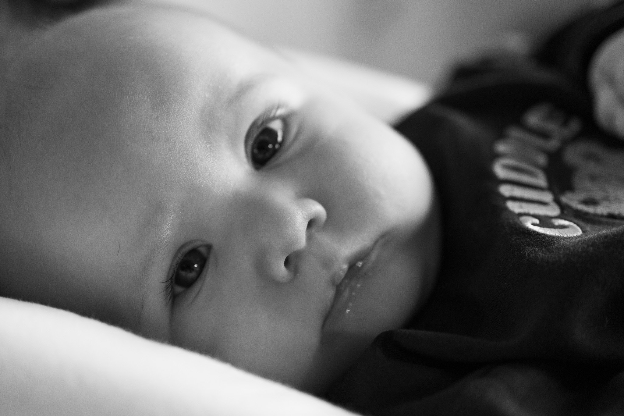 Close-up of a baby lying down, with visible eye, nose, and part of the cheek, in black and white.