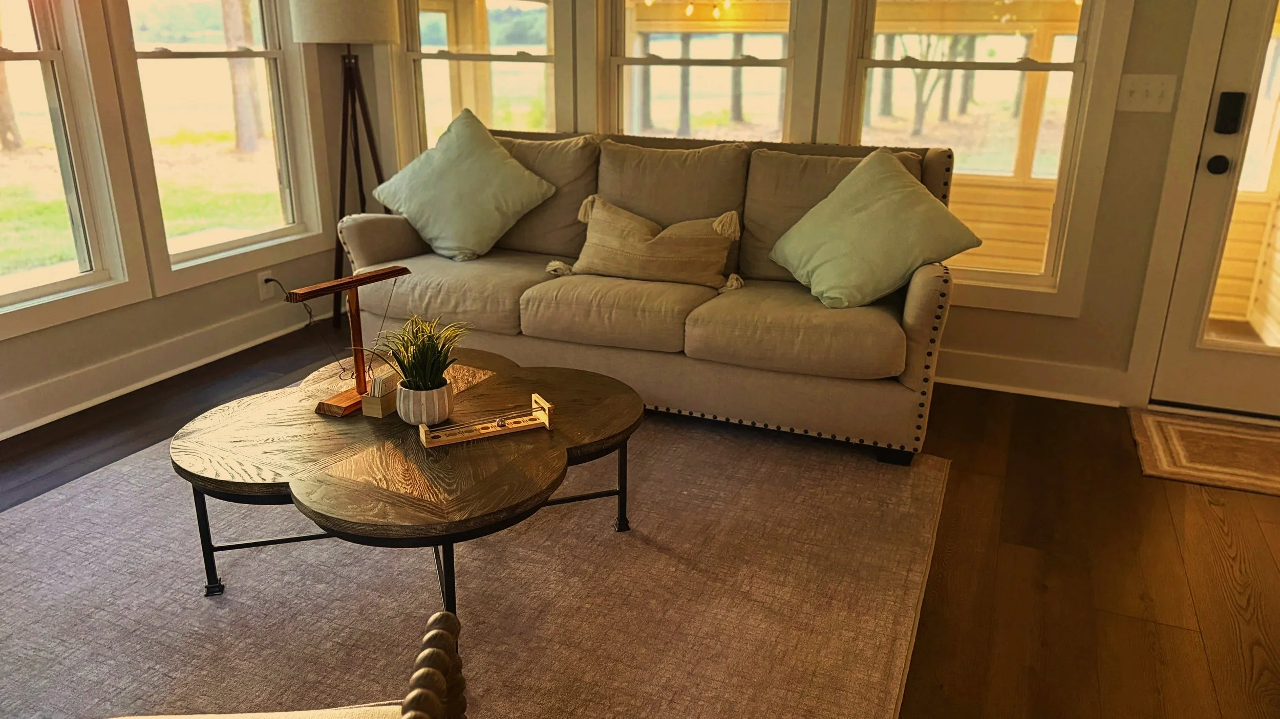 An immaculately staged and deep-cleaned sunroom featuring perfectly aligned furniture, pristine sage green pillows, and an orderly living space.⁠