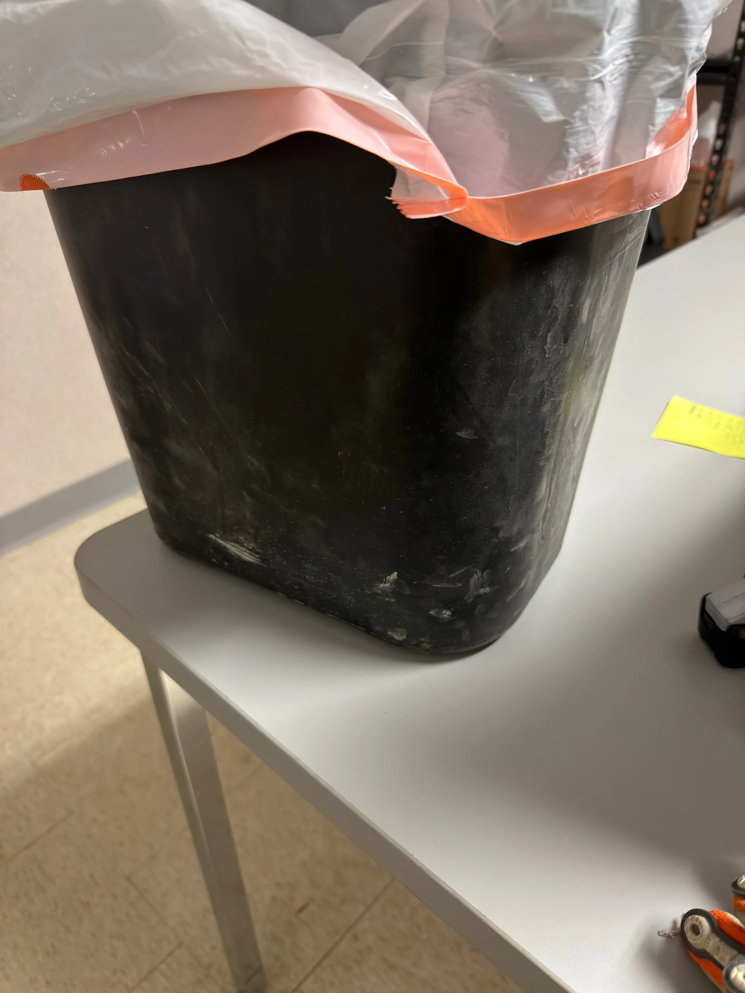 ⁠Before view of a dirty, heavily scuffed matte black plastic desk trash can sitting on an office workstation desk prior to detailing.⁠