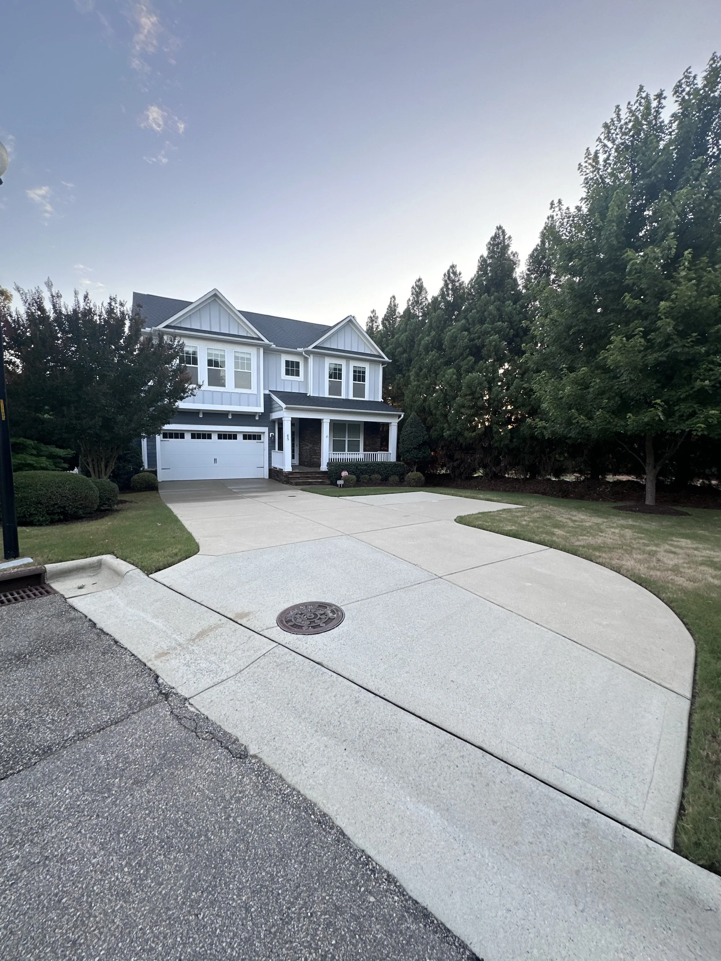 An exterior view of a pristine, freshly detailed residential driveway and beautiful two-story home in Flowers Plantation in Wendell, NC, prepared for the market by TerraPro.