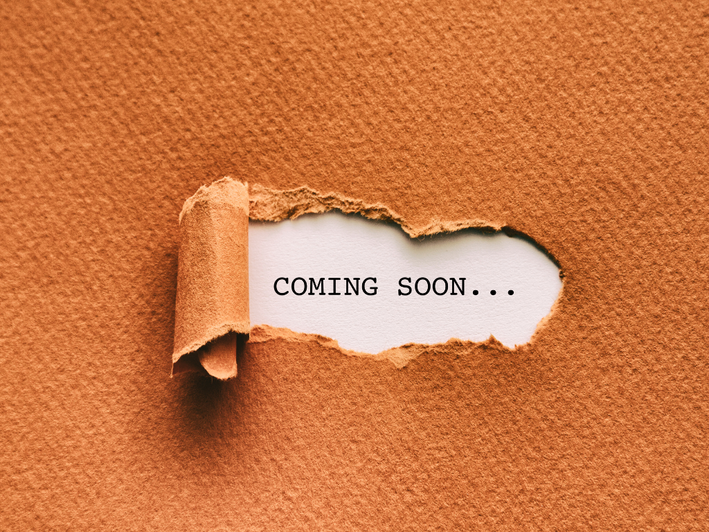 A torn piece of brown paper peeling back to reveal the words 'COMING SOON...' on a white background.