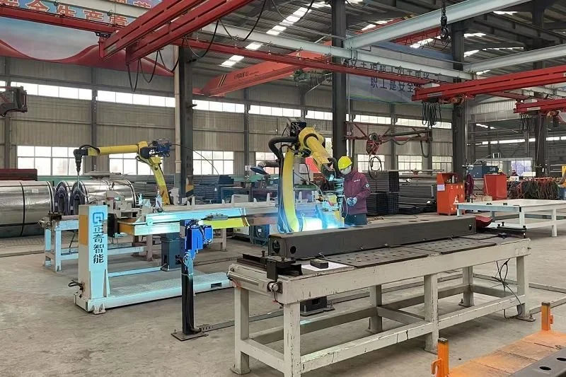 Robotic arms welding metal in an industrial factory, with workers observing, amid large machinery and metal materials.