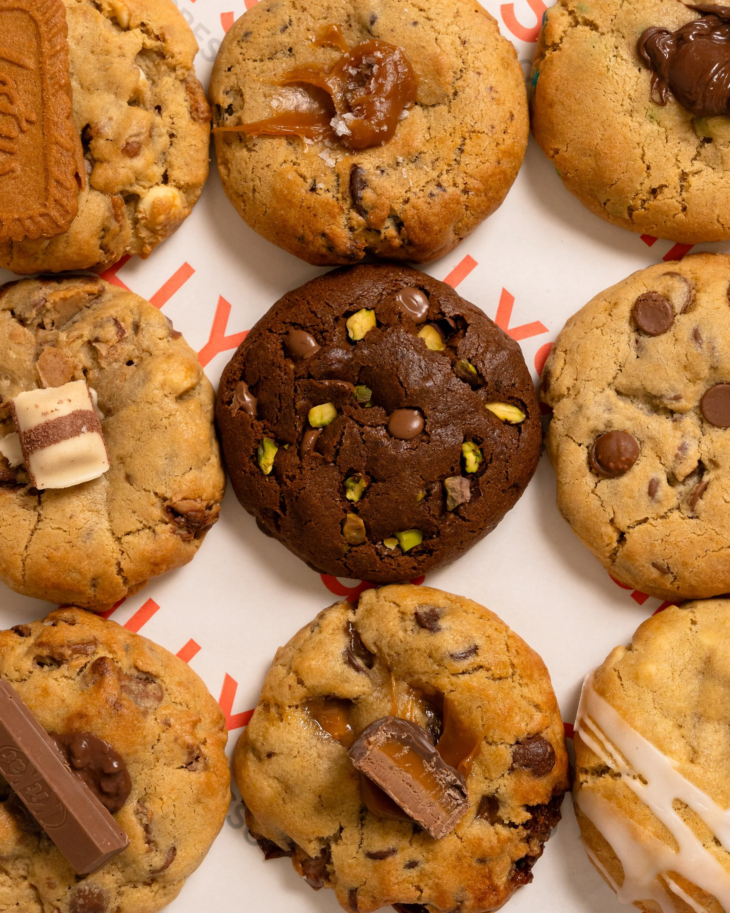 Close-up of various cookies, including chocolate chip, peanut butter, and those topped with caramel or chocolate
