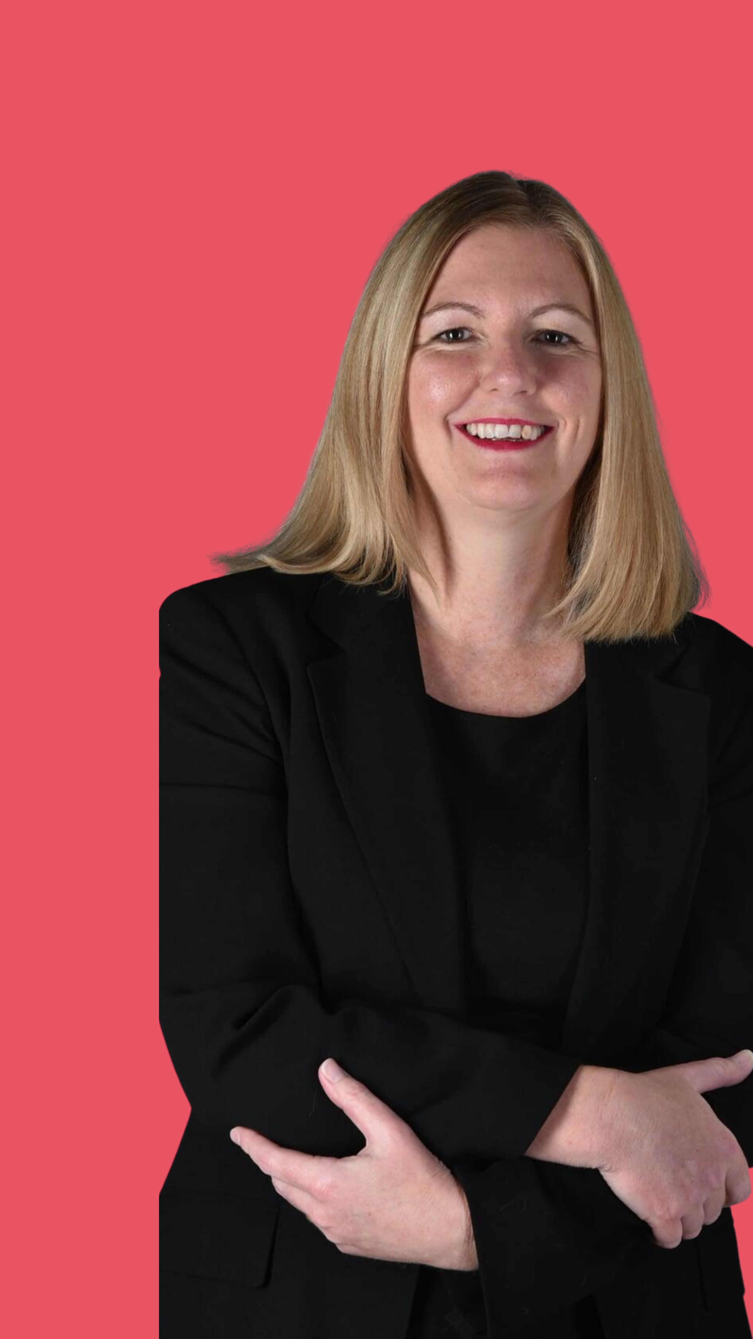 Portrait of a smiling woman with shoulder-length blonde hair, wearing a black blazer, standing against a pink background.