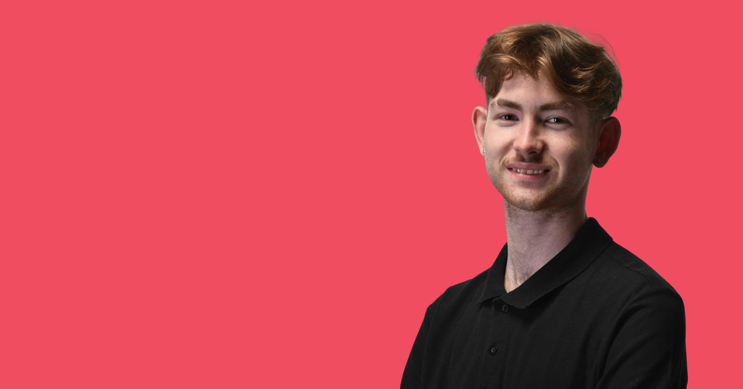 A young man with curly brown hair, fair skin, and a slight beard, wearing a black shirt, standing against a pink background, smiling softly.