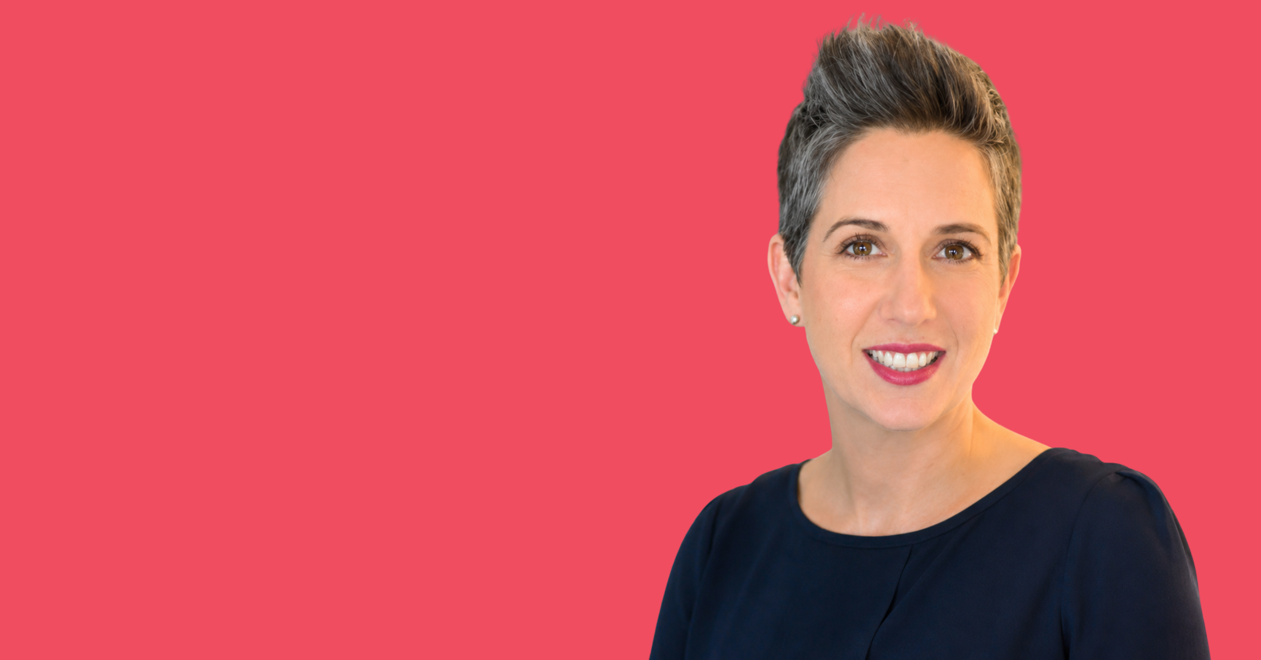 A woman with short gray hair smiling against a pink background.