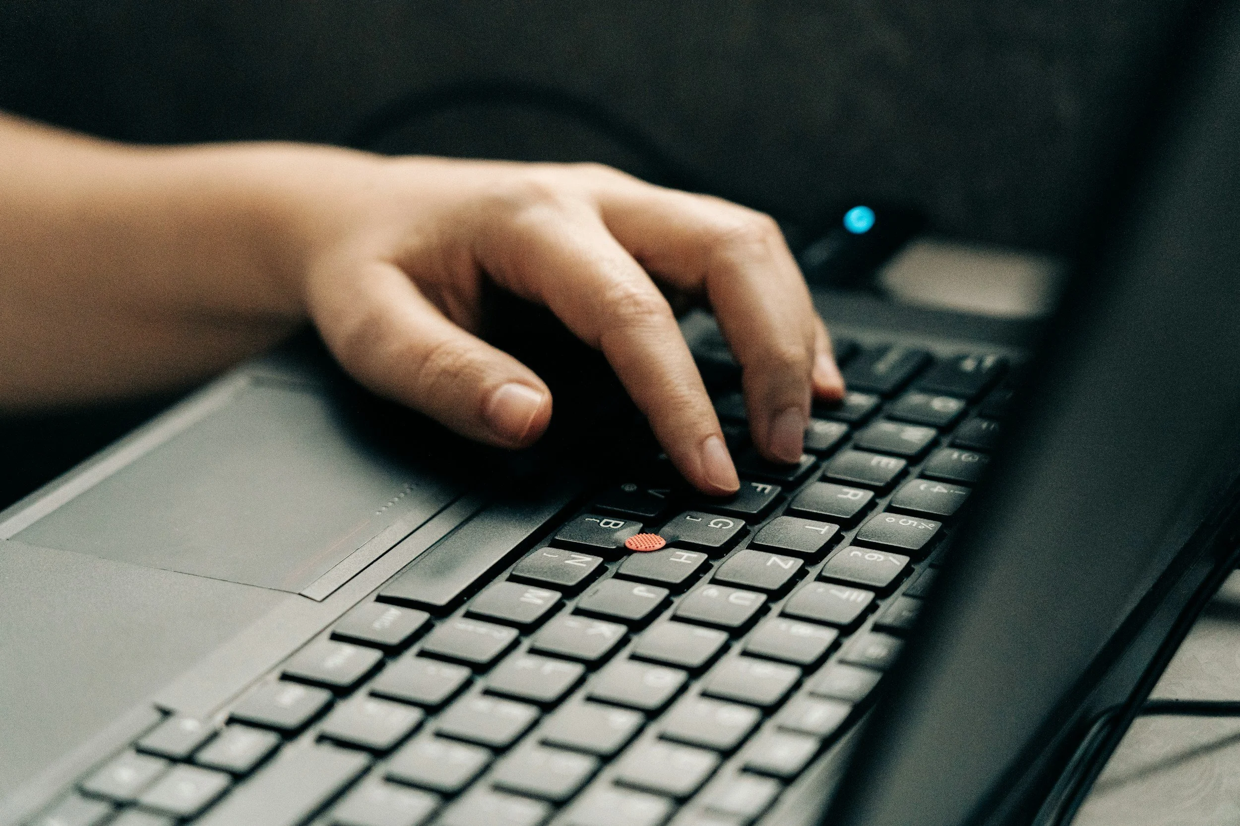 Close-up of a person's hand using a keyboard on a laptop computer.